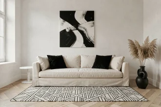 Salon minimaliste en noir et blanc avec canapé en lin crème, tapis géométrique et toile abstraite murale